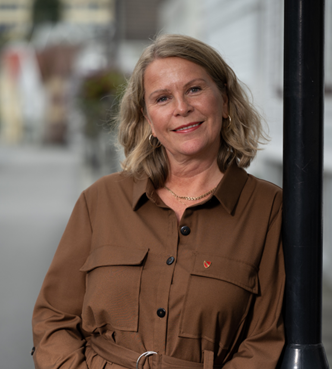 Dame som står inntil stolpe, brun kjole