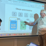 Mann som peker på obeya skjerm