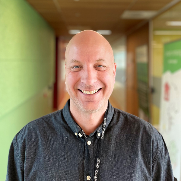 mann som smiler, skallet og har på en koksgrå skjorte